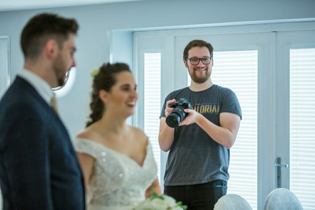 Why you should be crediting your photographer - picture of a photographer standing taking a photo of a couple getting married.