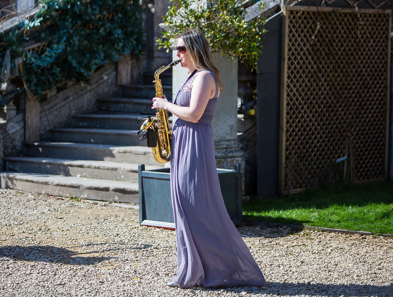 This image depicts a woman in a long dress playing a saxophone at a wedding reception.
